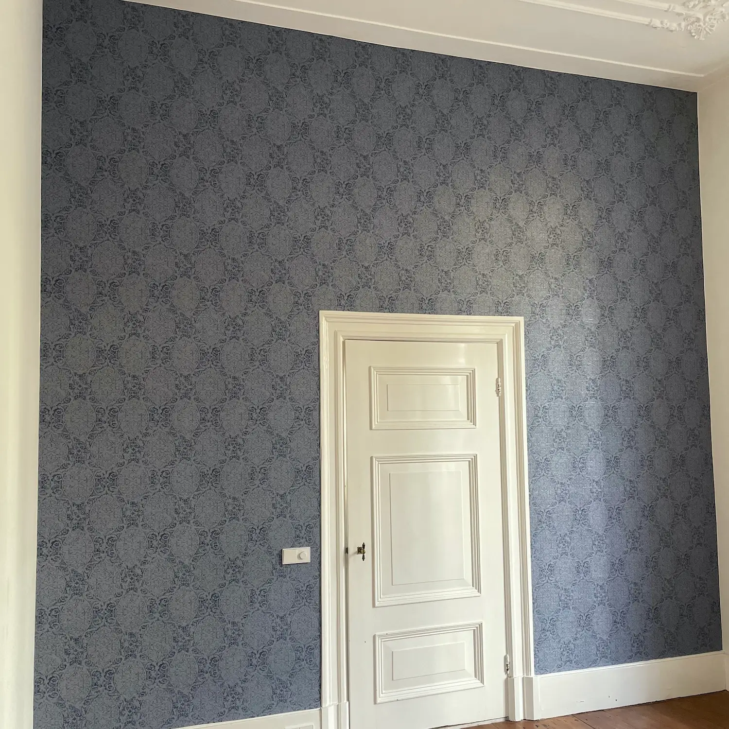 Hoge muur in oud huis behangen met klassiek historische blauw behang met frans patroon