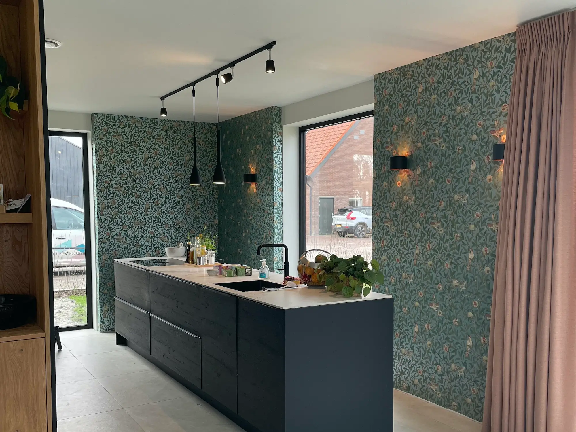 keuken met kookeiland met daar achter een strak behangen muur met groene blaadjes en bloemen