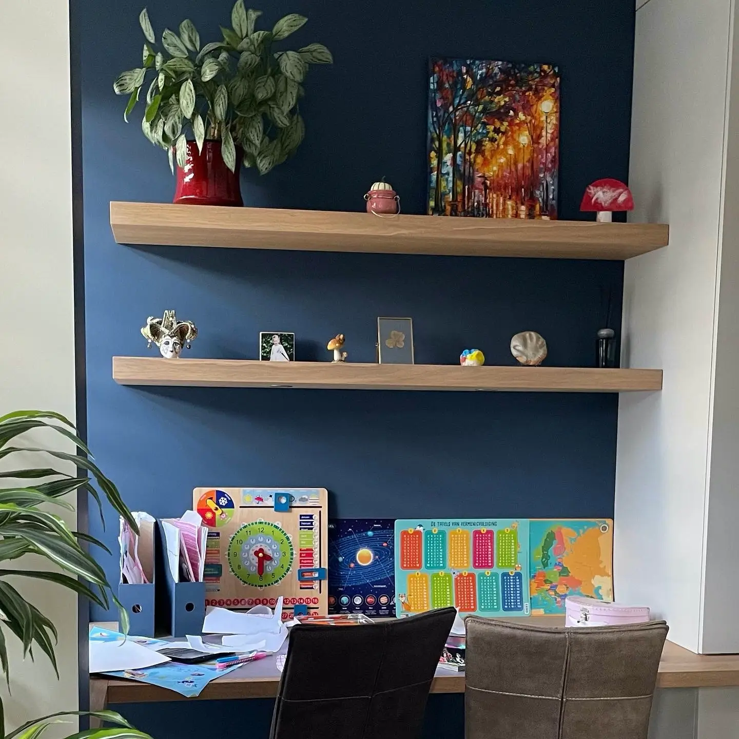 Kinderspeelhoek met bureau en twee boekenplanken en prachtige kleur donkerblauw op de muur.